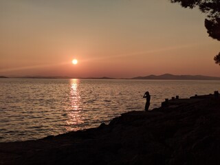 silhouette of a person on the rocky beach during sunset