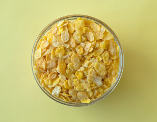 Bowl of cereal corn flakes on a yellow background. Flat lay style