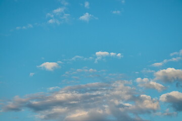 Obraz premium light blue sky, with small tufts of white clouds floating and shaded clouds on the horizon.