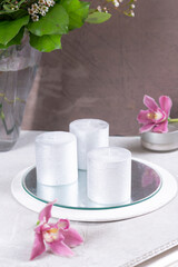 Silvery candles on a beige table with flowers