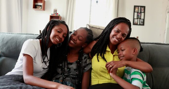 Black African mother and teen daughters and little boy son together at home sofa
