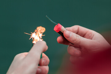 Man Lighting Up Firecracker in his Hand Against the Blue Background Using Gas Lighter