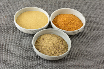 Ground white pepper, black pepper and red pepper spices in ingredient bowls on burlap
