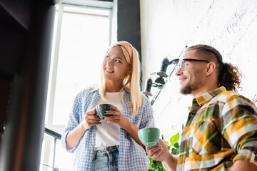  stylish couple looking away while standing on stairway in cafe with coffee cups