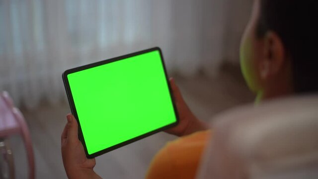A teenage boy is watching a tablet green screen.