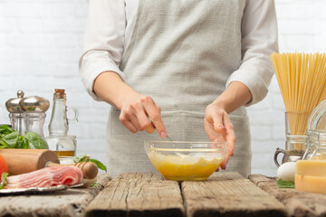 Macro shot view of chef mix eggs and milk in bowl for cooking pasta alla carbonara. Backstage of preparing traditional italian dish on white background. Frozen motion. Cookbook illustration.