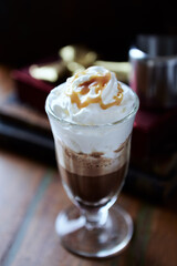 Coffee with whipped cream on dark wooden background. Close up.
