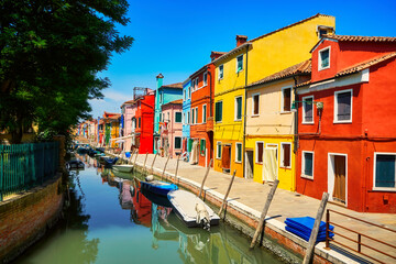Fototapeta na wymiar Burano traditional vivid colorful houses vibrant colors island tourism landmark cityscape. Sea canal with boats and bright paint facade old historic scenic place. Venice Italy