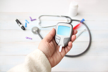 digital blood glucose meter in female hands, laboratory test tube with blood, medical stethoscope, health concept, Checking Blood Sugar Level With Glucometer