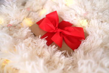 gift box with a red bow, cozy white fluffy plaid, garlands are glowing, concept of holidays, valentine's day, mother, merry christmas