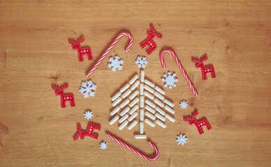 Christmas tree made of white capsules surrounded with red and white Christmas decorations and ornaments on wooden background with copy space. Medical, medication or pharmacy background.