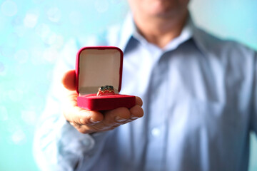 man holds out a red box with jewelry, a gift for a holiday, opens it, concept of a holiday, anniversary of a married couple, valentine's day, mother, merry christmas
