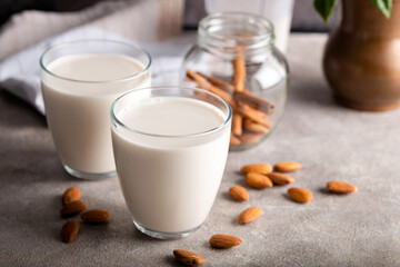 Homemade organic almond milk in a glass on stone background with cinnamon sticks.