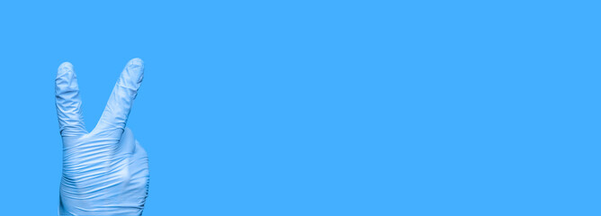 Hand Wearing Surgical Glove with Victory Gesture. V-sign. Fighting Covid-19. Gloved Hand Shows Number Two. Doctor's Hand Showing 2 Fingers. Victory Coronavirus. Gloved Hand Shows Victory Symbol.