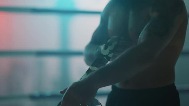 Boxer in the boxing gym. Bandages his hands. Sparring in the ring. Boxer jumping rope. Exercise with ropes. Round one. Fog in the ring. Zetsky sport. Beautiful backlight. World boxing champion.

