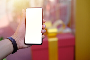 Man holding blank white screen smartphone with blue gift box background, Technology concept.