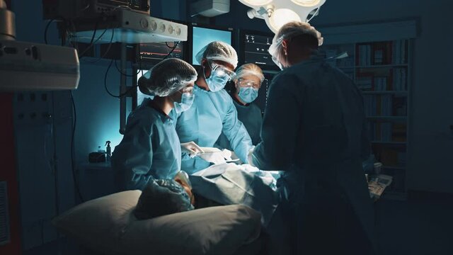 Experts in saving lives. High angle of team of professional surgeons and nurses brainstorming while working at hospital performing surgical procedure in operating theatre. Professionalism experience