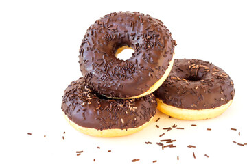Three chocolate glazed sweet donuts with sprinkles on an isolated white background.