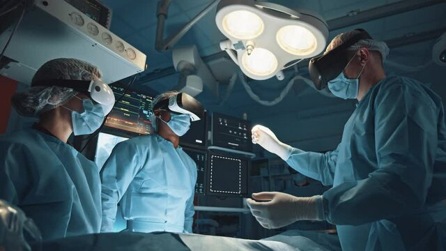 Group of surgeons using augmented reality holographic hololens glasses while operating in modern operation theater. Testing result and human anatomy on technological digital virtual interface concept
