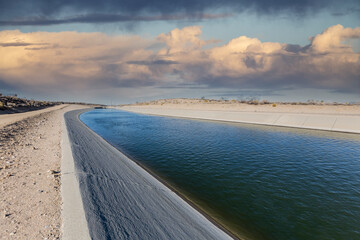 California aqueduct with storm sky in the Mojave desert area of northern Los Angeles County.. - obrazy, fototapety, plakaty