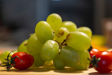 fresh grapes and cherry tomatoes on a wooden board