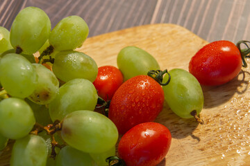 fresh grapes and cherry tomatoes on a wooden board