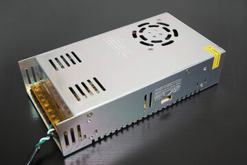 Inexpensive 14 Volt DC switching power supply on black desk