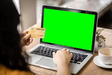 Close-up of freelance people business female Hand holding Credit cards casual working using with laptop computer with a blank green screen in coffee shop like the background,Online payment shopping
