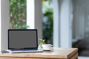 Mockup of laptop computer with empty screen with coffee cup and smartphone on table of the coffee shop background,White screen