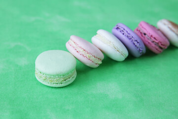 colorful macaroons or macarons on a green background with copy space for text. delicious french dessert. close-up. 