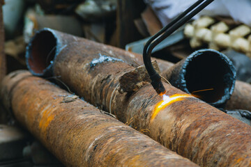 Scrap yard, cutting used pipes with gas equipment, metal for recycling.