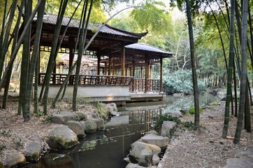 Obraz premium Wooden shelter in bamboo forest next to a stream. Suzhou, China.