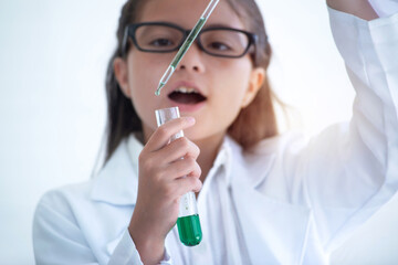 Young girl in a lab coat uses a test tube to experiment in chemistry class, and holds test tube in his hands