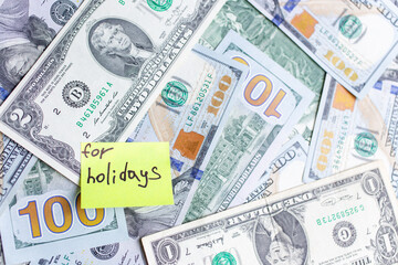 Yellow stick notes on an USD money background. Saving money for holidays concept