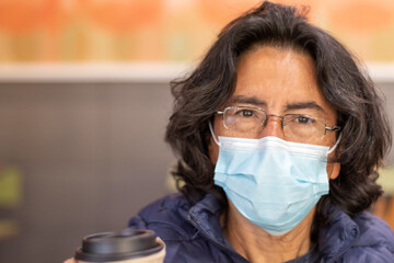 man with a face mask holding a cup of coffee