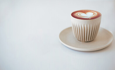Close-up. latte art coffee in ceramic cup with white heart cream on top on white table