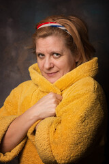 Portrait of a woman in a yellow robe. Warm and cozy home clothes. Dark vintage background. Painting reproduction.