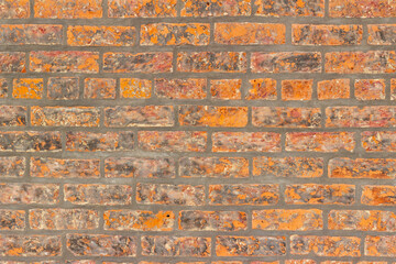 Full frame shabby chic vintage brick wall texture background, with fiery hot looking bricks in burnt shades of orange, red and brown