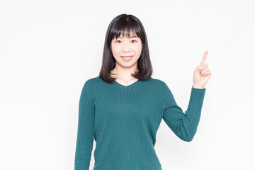白背景の前に立って人差し指でポイントを示す女性