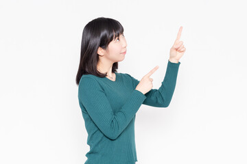 白背景の前に立って人差し指でポイントを示す女性