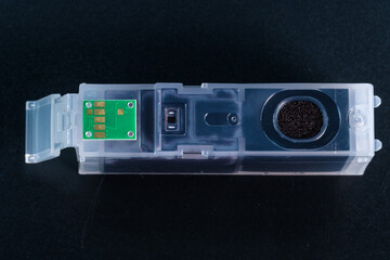 Makro - Blick auf Details: Eine schwarze Tintenpatrone mit einem grünen Chip für einen Tintenstrahldrucker auf einem schwarzen Hintergrund