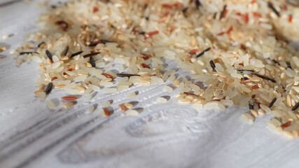 A pile of unboiled fresh rice of various varieties is scattered on the white table. Copy space.