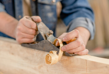 Hands of a carpenter planed wood in a workshop