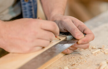 Fototapeta na wymiar Hand of a carpenter taking measurement of a wooden plank