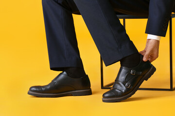 Young man in stylish shoes on color background