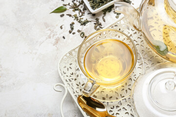 Tray with cup of hot tea, sugar and tea pot on table