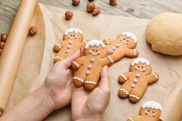 Woman holding Christmas gingerbread cookies on wooden background