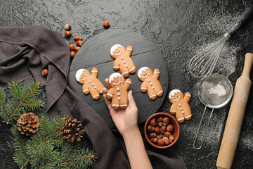 Woman holding Christmas cookie on dark background