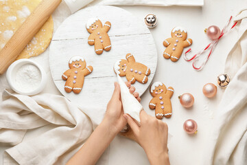 Woman decorating Christmas gingerbread cookies on table