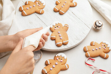 Woman decorating Christmas gingerbread cookies on table